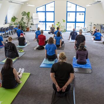 Gruppe Mitarbeiter im Sitz auf der Matte während eines Rückenworkshops